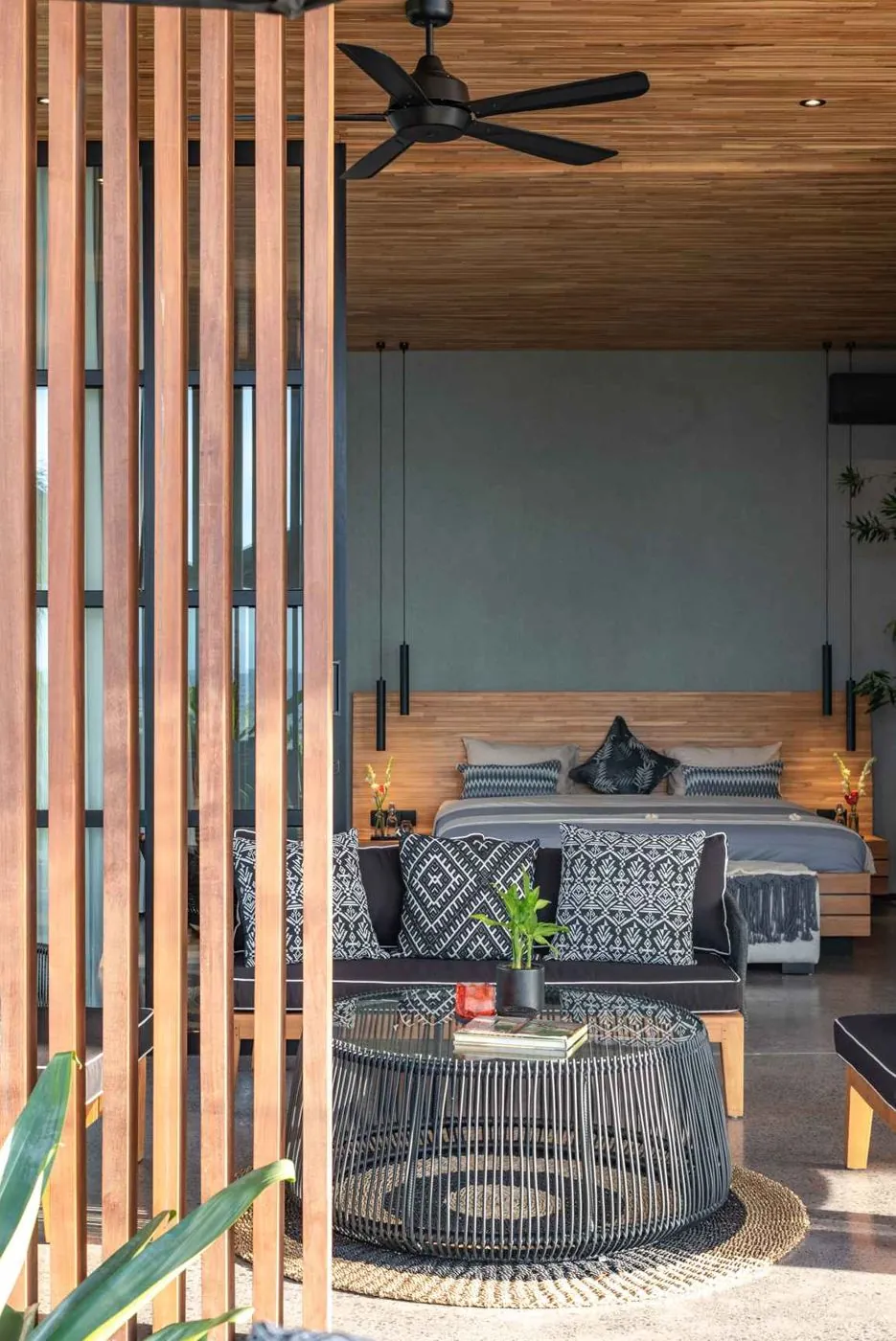 A suite seen through the timber slat screen, fan turning over the bed