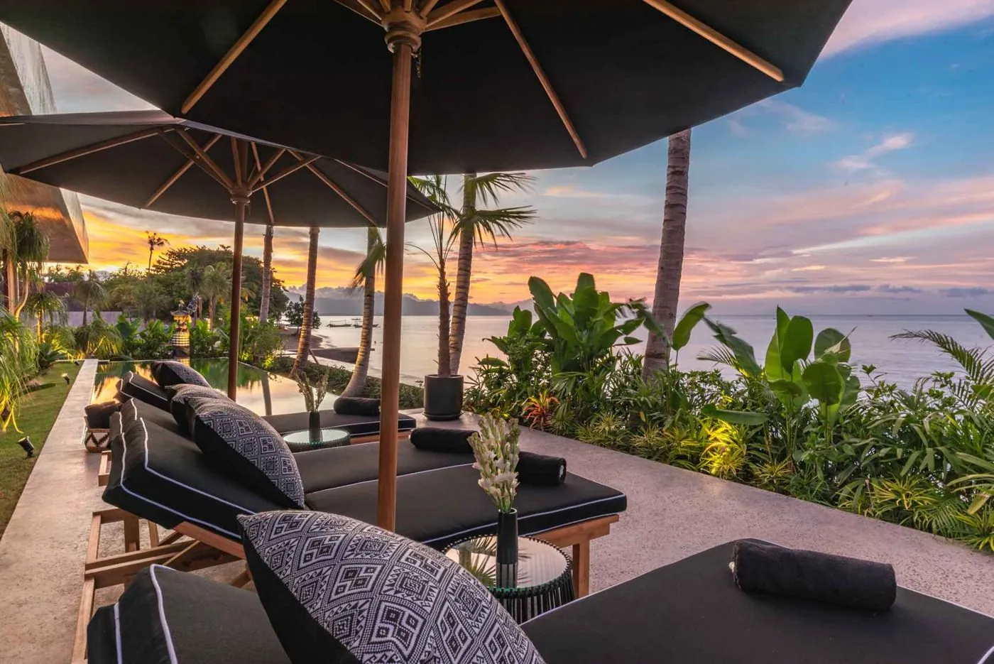 Umbrellas over the loungers as the sky turns, pool and bay beyond