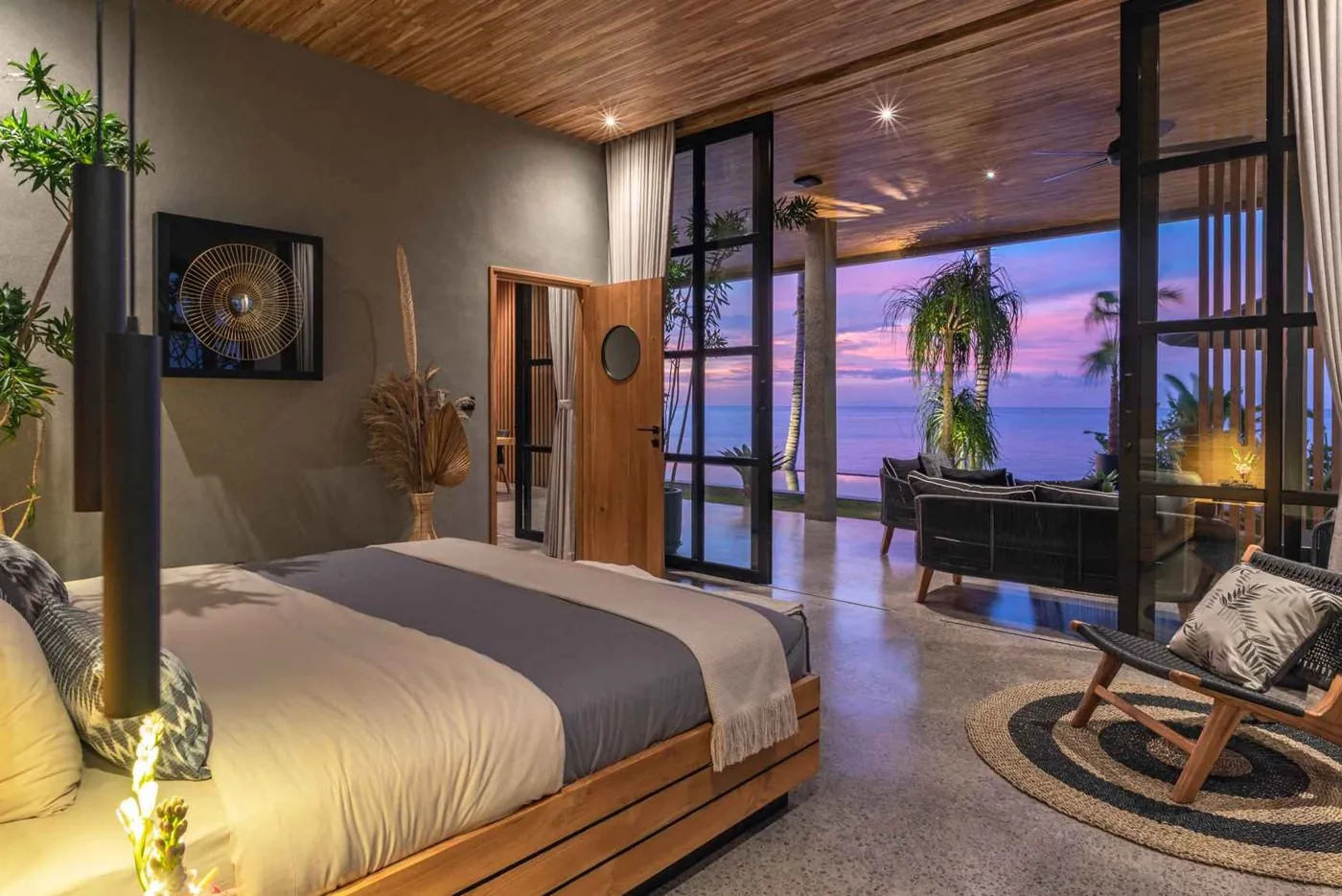 The master suite at dusk, doors open to the sea