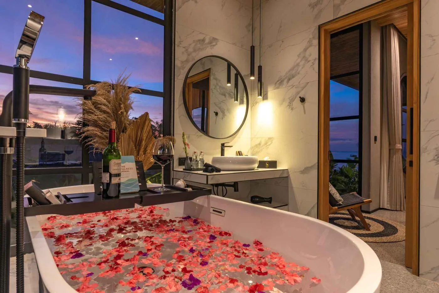 The petal bath drawn at sunset, wine on the caddy