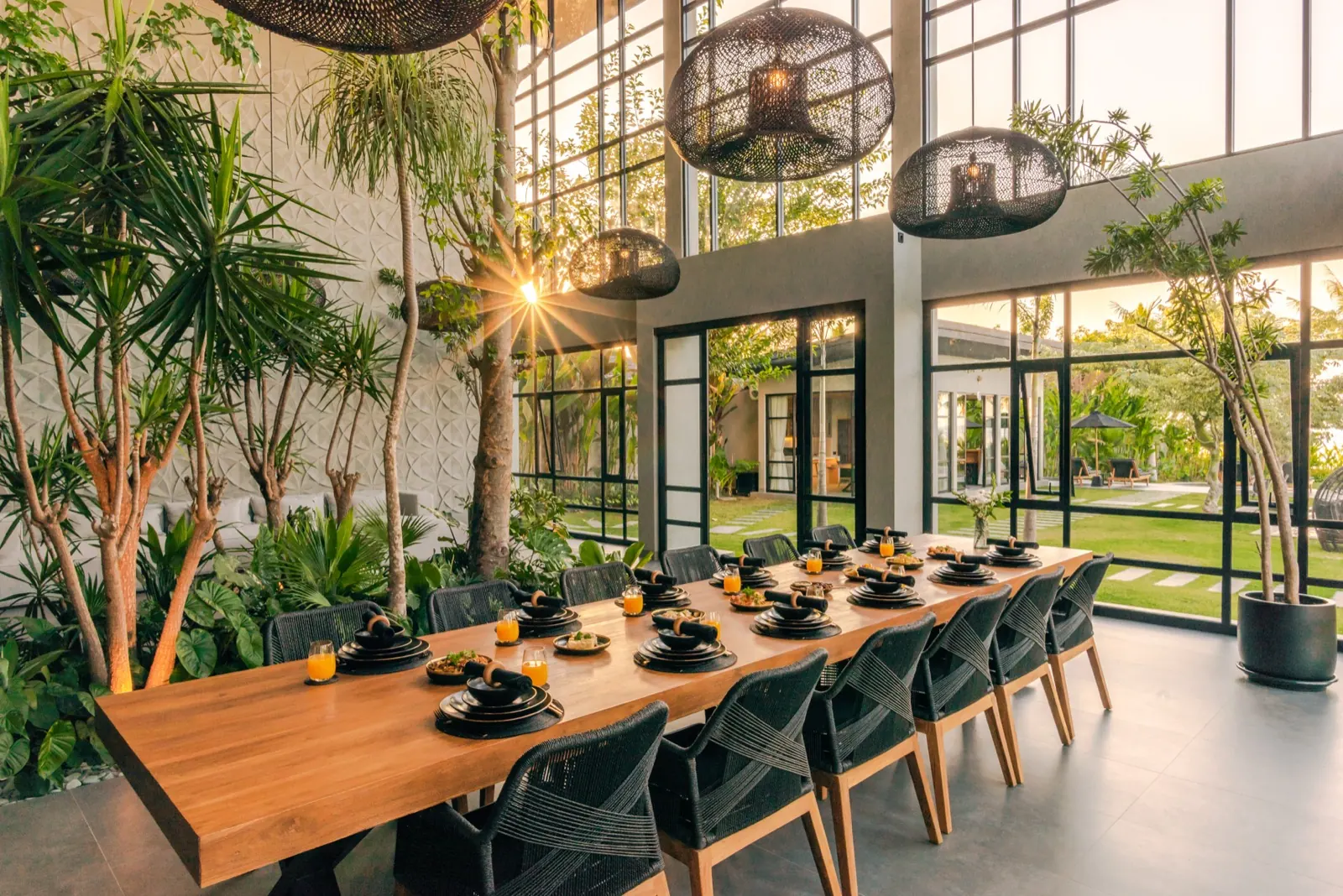 The long dining table set for the whole party under rattan pendants