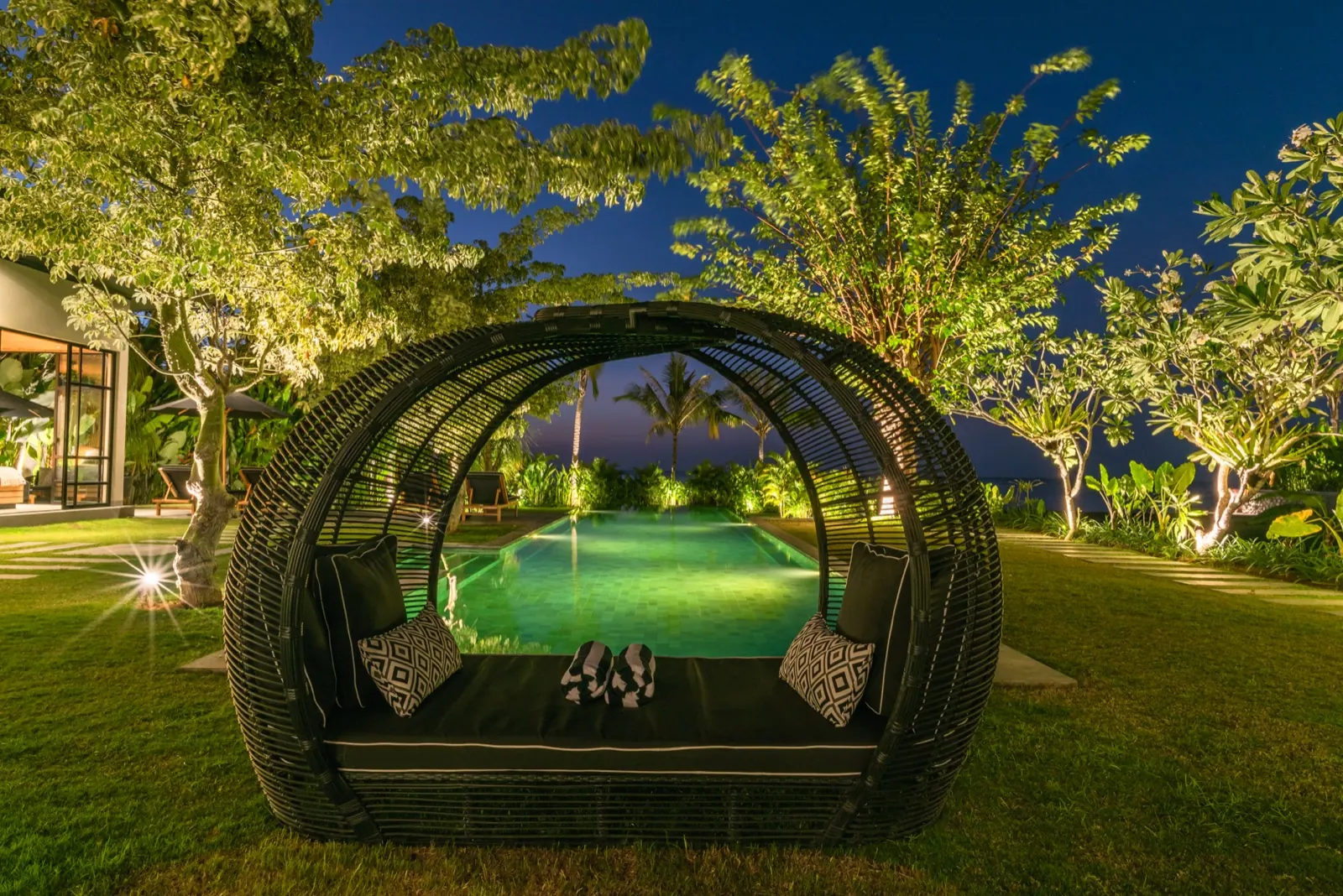 The rattan daybed glowing beside the pool at night