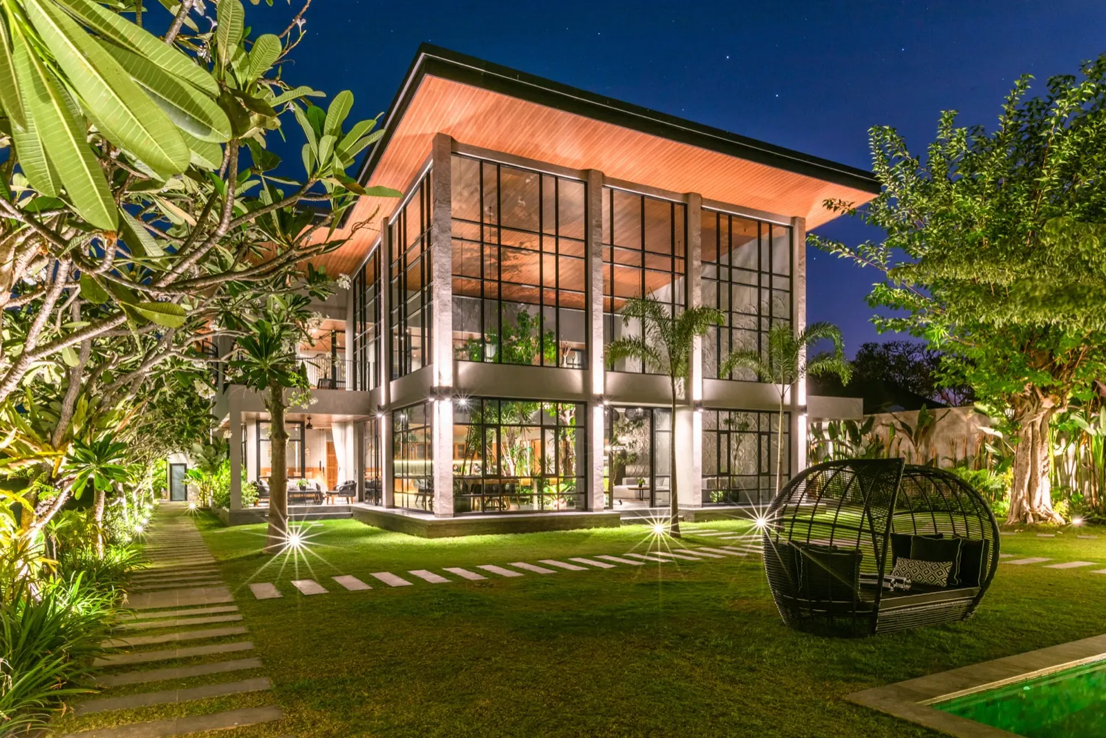 The glass hall at night from the garden, daybed on the lawn